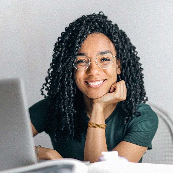 woman smiling at camera while working on her laptop